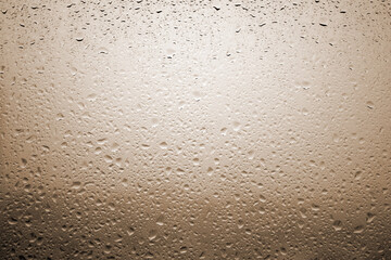 Drops of rain on a window glass with very diffuse landscape copper orange color