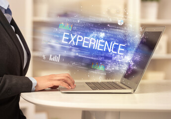 Closeup of businessman hands working on laptop with EXPERIENCE inscription, succesfull business concept