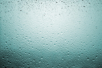 Drops of rain on a window glass with very diffuse landscape cobalt blue color