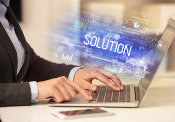 Closeup of businessman hands working on laptop with SOLUTION inscription, succesfull business concept