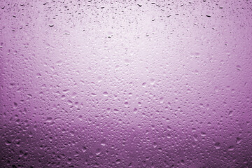 Drops of rain on a window glass with very diffuse landscape lilac color