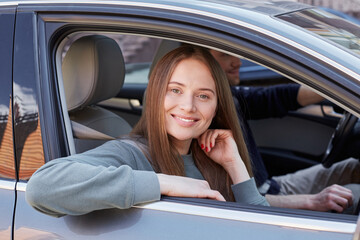 Adorable smiling lady sitting with her arm outside the car