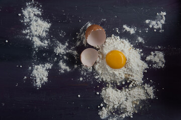 Broken egg on a table with wheat flour, ingredients for making cake