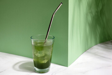 Green fresh cold drink with ice on green background
