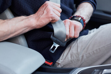 Male driver buckling up in his modern auto
