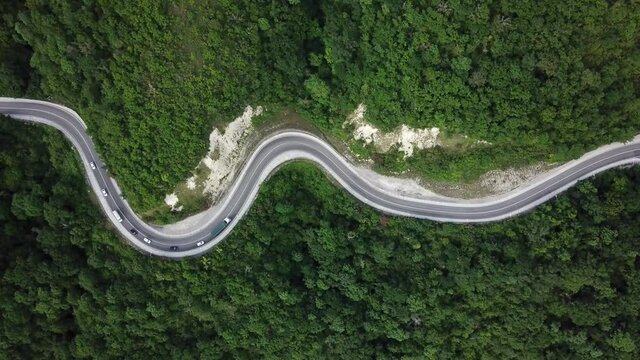 Mountain winding zig zag road. Top aerial view: cars driving on road from above.