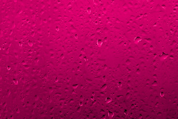 Water drops on glass with vivid medium contrast reddish pink color