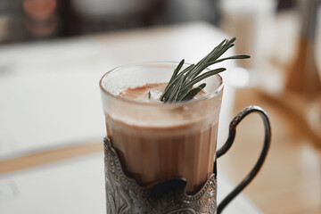 A mug of hot cocoa with a rosemary branch in a vintage metal cup holder. Retro style food photo...