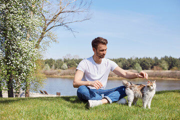 Naklejka na ściany i meble Calm young male relaxing with his pet outdoors