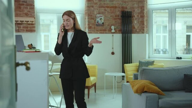 Angry serious businesswoman talking on cellphone at home kitchen upset mobile cellphone speaking female modern frustrated slow motion