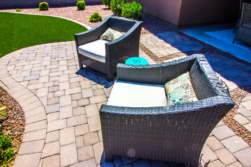 Two Wicker Patio Chairs On Outdoor Pavers