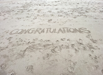 Congratulations written in the sand.