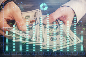 Multi exposure of financial graph drawing hologram and USA dollars bills and man hands. Analysis...