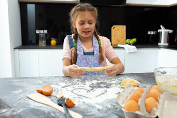 Adorable girl making cookies in kitchen at home