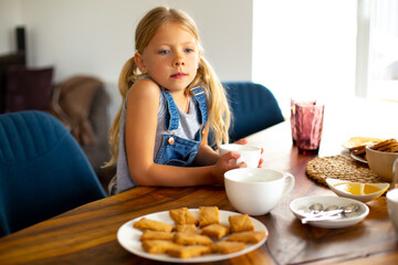 Adorable little girl drinking tea at home