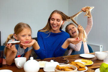 Cheerful mother having breakfast with adorable daughters