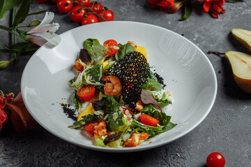 Traditional shrimp and mango salad in a restaurant. Fried shrimp salad with rosemary, mango, cherry tomatoes, salad mix, mango chili sauce.