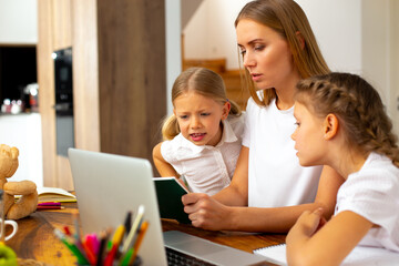 Fototapeta premium Mother helping her daughters to study at home
