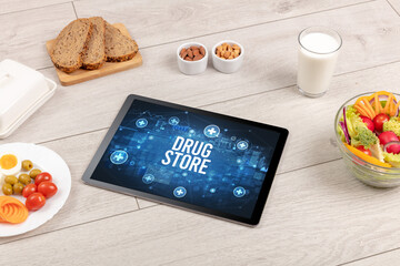 DRUG STORE concept in tablet pc with healthy food around, top view