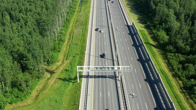 Asphalt ringroad around big city. Speedway with cars through green field. Aerial view from drone