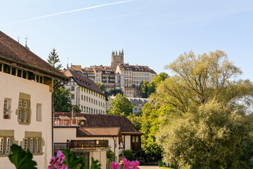Fototapeta na wymiar Beautiful scenery of apartment buildings in old town of Fribourg, Switzerland, with Cathedral Saint Nicolas in the background.