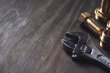 Plumbing. Different wrenches, pipe, tube, fittings and connectors on a wooden rustic table.