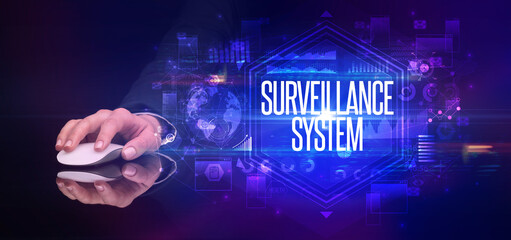 hand holding wireless peripheral with SURVEILLANCE SYSTEM inscription, cyber security concept