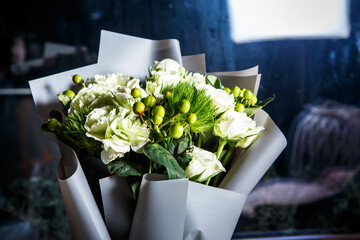 closeup exquisite bouquet of big white roses and fresh greenery in gift craft paper