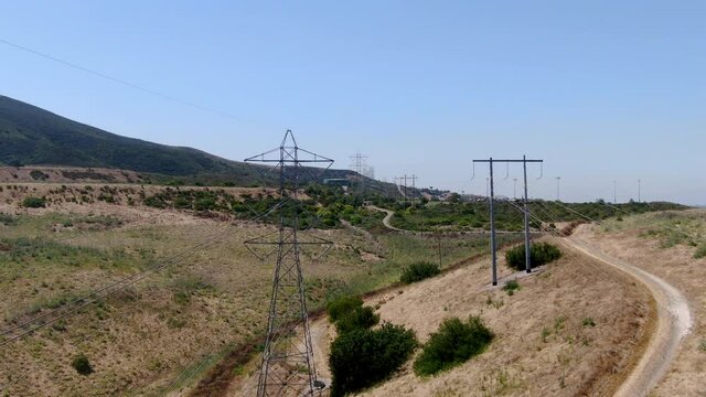 Aerial view of electricity transmission pylon in dry valley landscape. High voltage electricity distribution, California