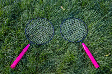 Isolated small badminton tennis rackets laying on grass ground. Rackets on paver patio floor. - 357960393
