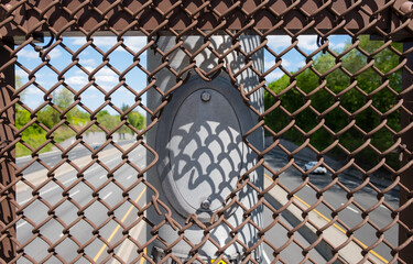 Outdoor electric pole isolated with highway background. Chain link fence with cutout for industrial light pole.  - 357960746