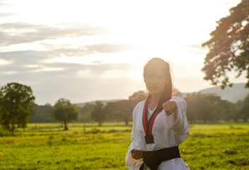 Woman training taekwondo sunset.Photos is backlit