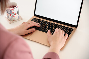 Woman hands using a gold laptop, incredibly thin, light and perfectly portable notebook open with...