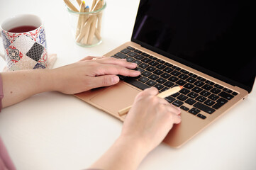 Woman hands using a gold laptop, incredibly thin, light and perfectly portable notebook open with...