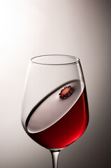 A glass of red wine with crown-looking surface impact of a wine drop.