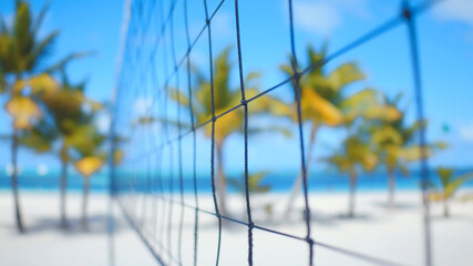 Close-up of volleyball net on tropical beach. Blue sky and palms of the Caribbean sea. Punta Cana,...