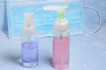 Spray and gel for cleaning surfaces and hands on the background of a medical mask. Selective focus.