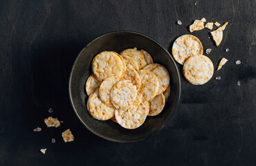 Round crispy rice and corn crackers in black bowl. Dietary concept and healthy vegetarian food.