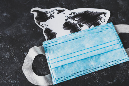 new normal after covid-19, world map with coronavirus mask on top of business desk