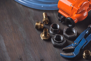 Plumbing. Different wrenches, pipe, tube, fittings and connectors on a wooden rustic table.