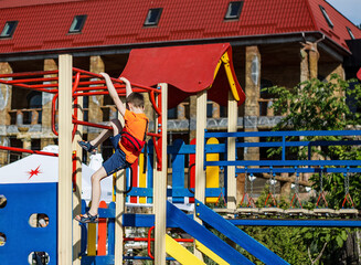 Fototapeta na wymiar Nikolaev, Ukraine- June 6, 2020: little boy climbs the horizontal bars on the playground