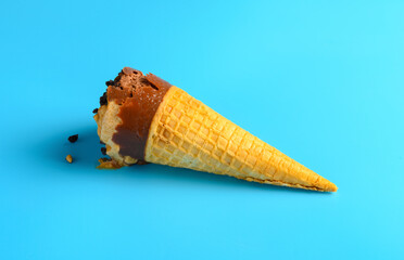 chocolate and coffee flavor ice cream cone starts melt on blue background