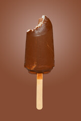 fresh chocolate outer popsicle with a bite on brown background