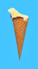 side view fresh pineapple ice cream cone with couple of bites on blue background