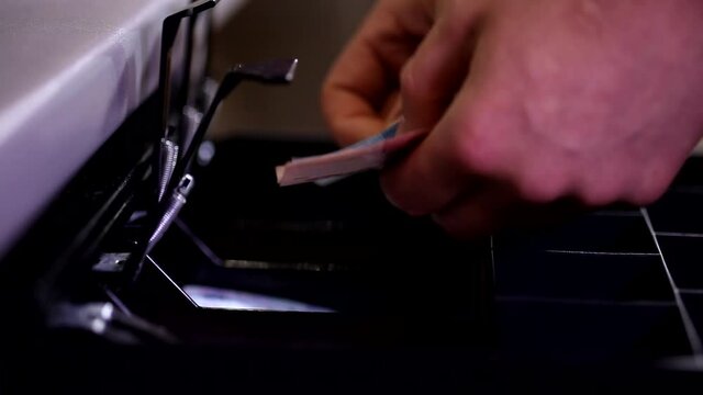 Close up shot of male cashier hands putting money counting banknotes in open cash register black drawer
