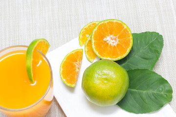 Tangerine in a white dish, cut in half with orange juice in a glass