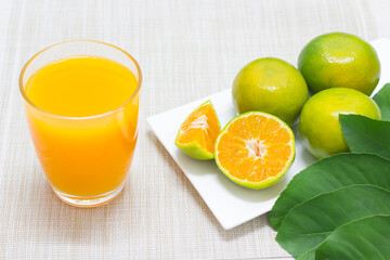 Tangerine is sliced in half in a white dish, ready when put in a glass and sliced oranges decorate the edges of the glass.