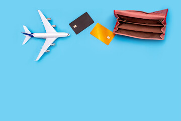 an empty wallet, a plane, and plastic cards on a blue background with space for text. It symbolizes the lack of money for flights and travel, problems and lack of money for airlines