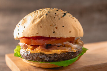 hamburguesa de carne de entraña argentina, con tomate, queso, panceta y lechuga en primer plano con foco selectivo sobre un fondo de madera