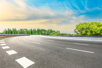 Fototapeta premium Empty asphalt road and green forest under blue sky.